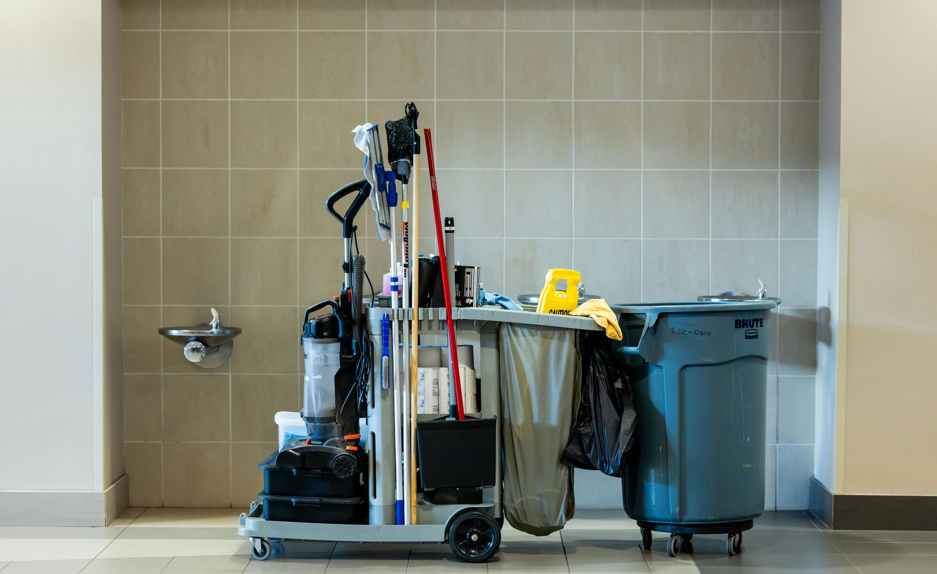A comprehensive collection of professional cleaning tools on a cart in an indoor environment.